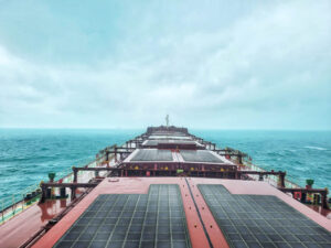 Long exposure view of a big cargo ship sailing in the middle of the sea under foggy overcast sky