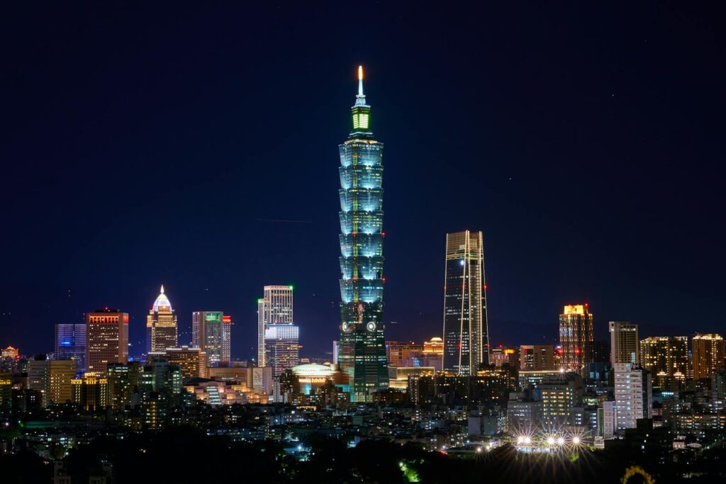 Illuminated Taipei 101 and city skyline at night showcasing modern urban architecture.