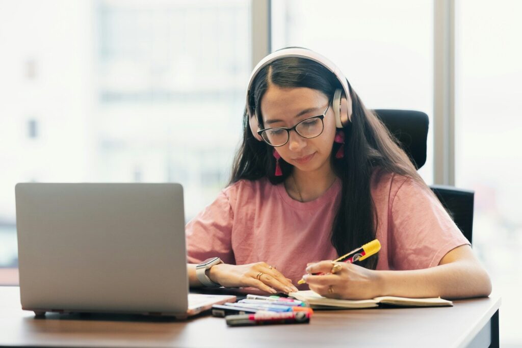 Young woman wearing headphones studying at desk